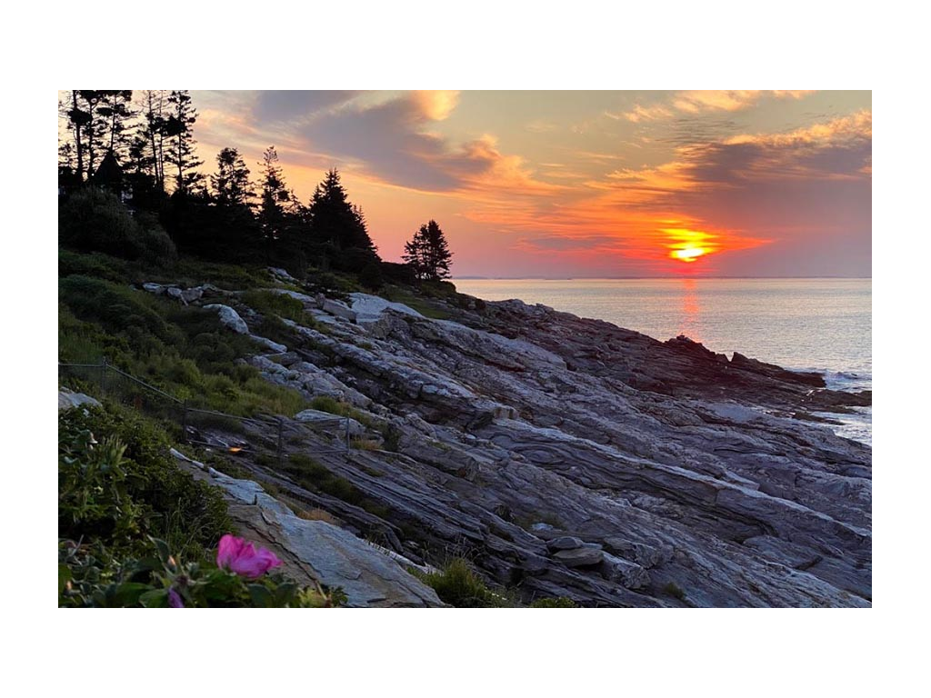 Coast in Maine with colorful sunrise in background