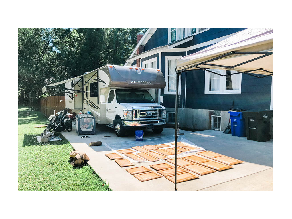 Cabinet doors laid out on driveway next to Minnie Winnie ready to be painted.