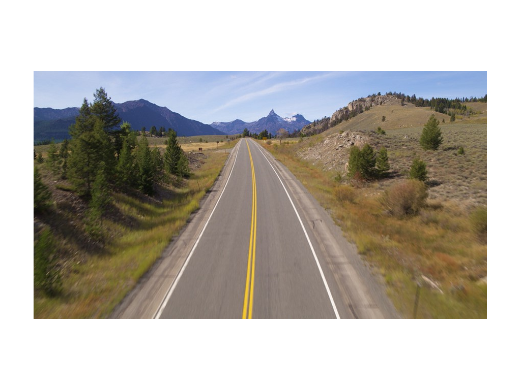 A long, open road with mountains in the distance