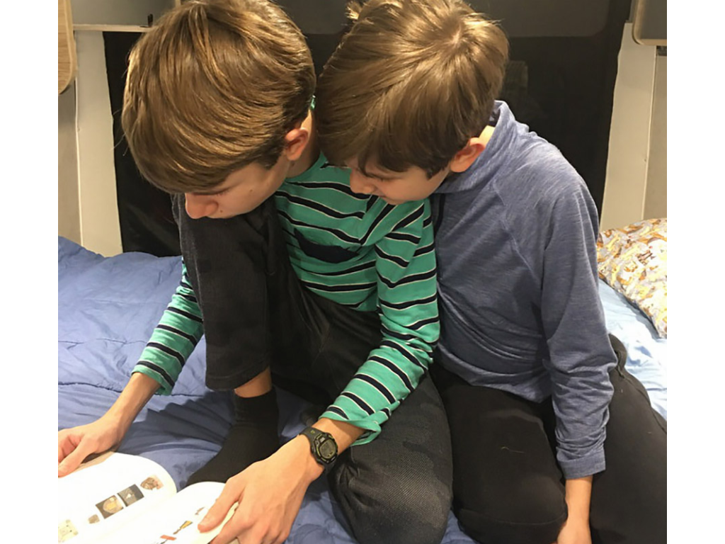 Boys sitting on bed reading a book together