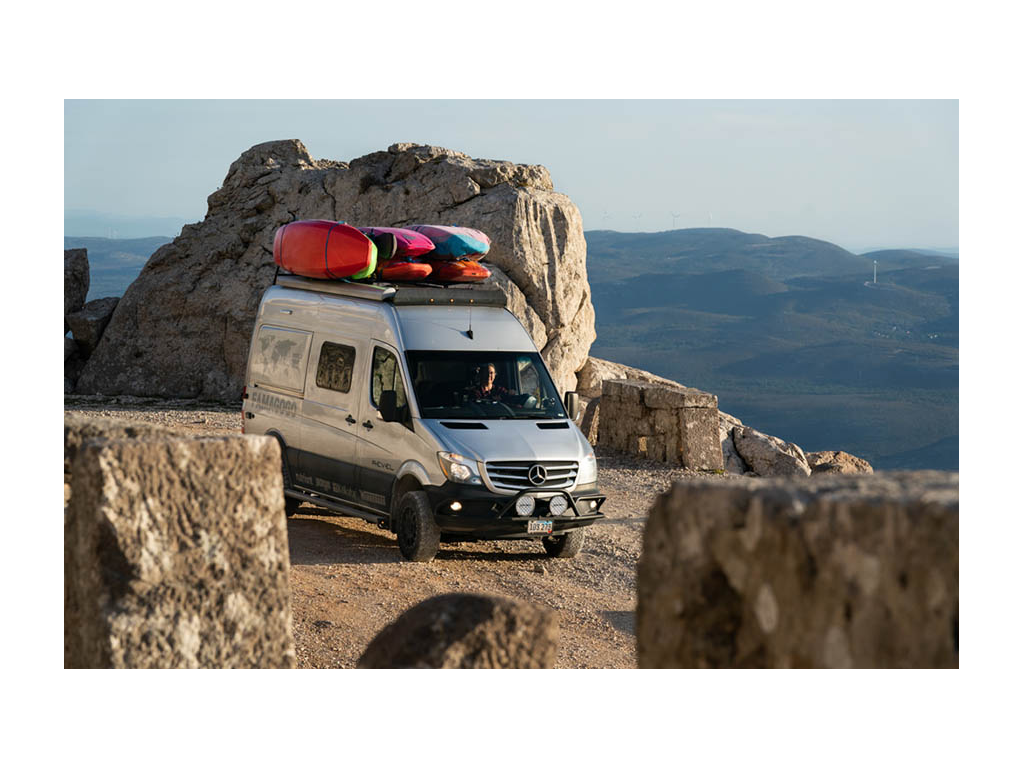Kathy driving Revel with kayaks on top