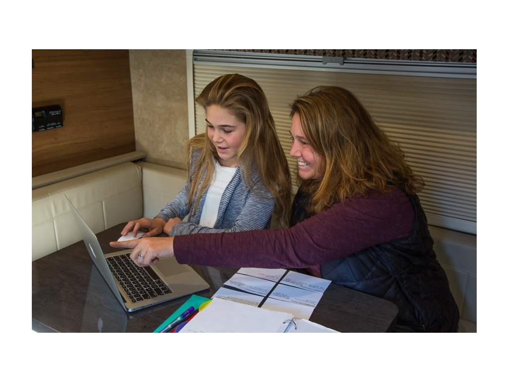 Abby and Kathy sitting at dinette doing school work on laptop