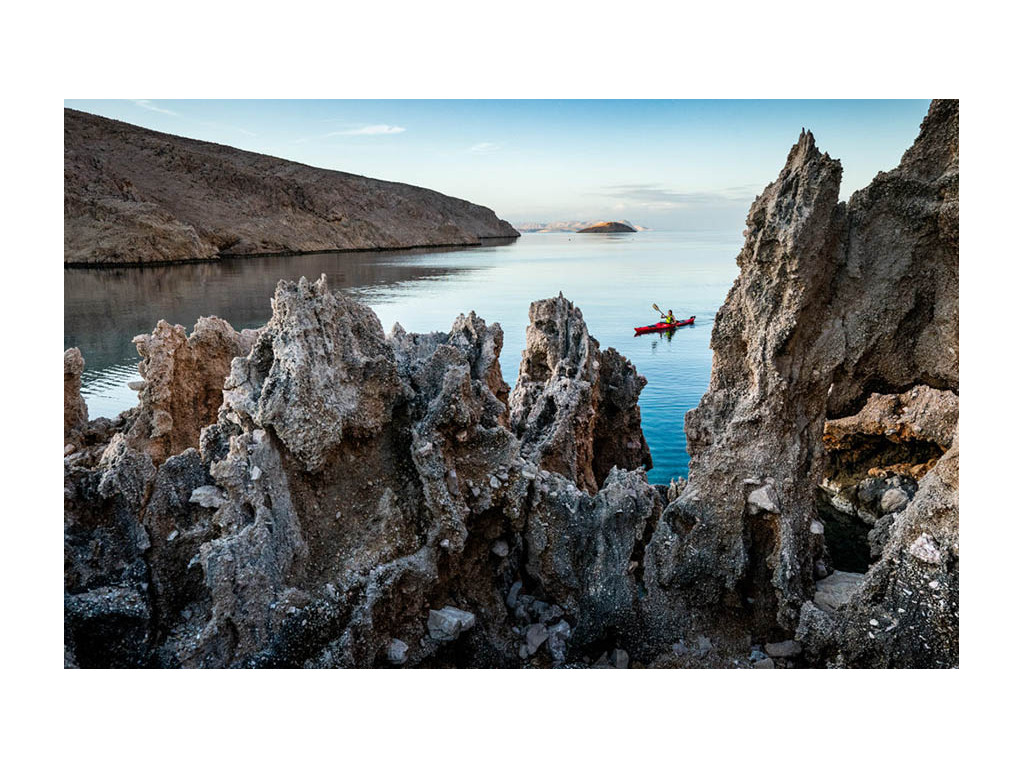 Gargoyles in sea cliffs with Kathy on kayak in background