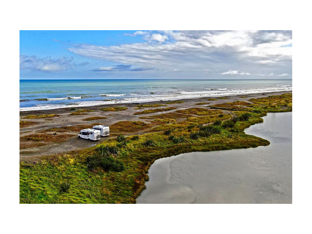 Aerial photo of two RVs parked next to each other on beach in New Zealand