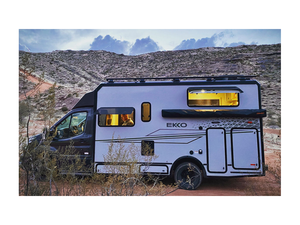 Exterior of EKKO parked in desert with windows open and lights on