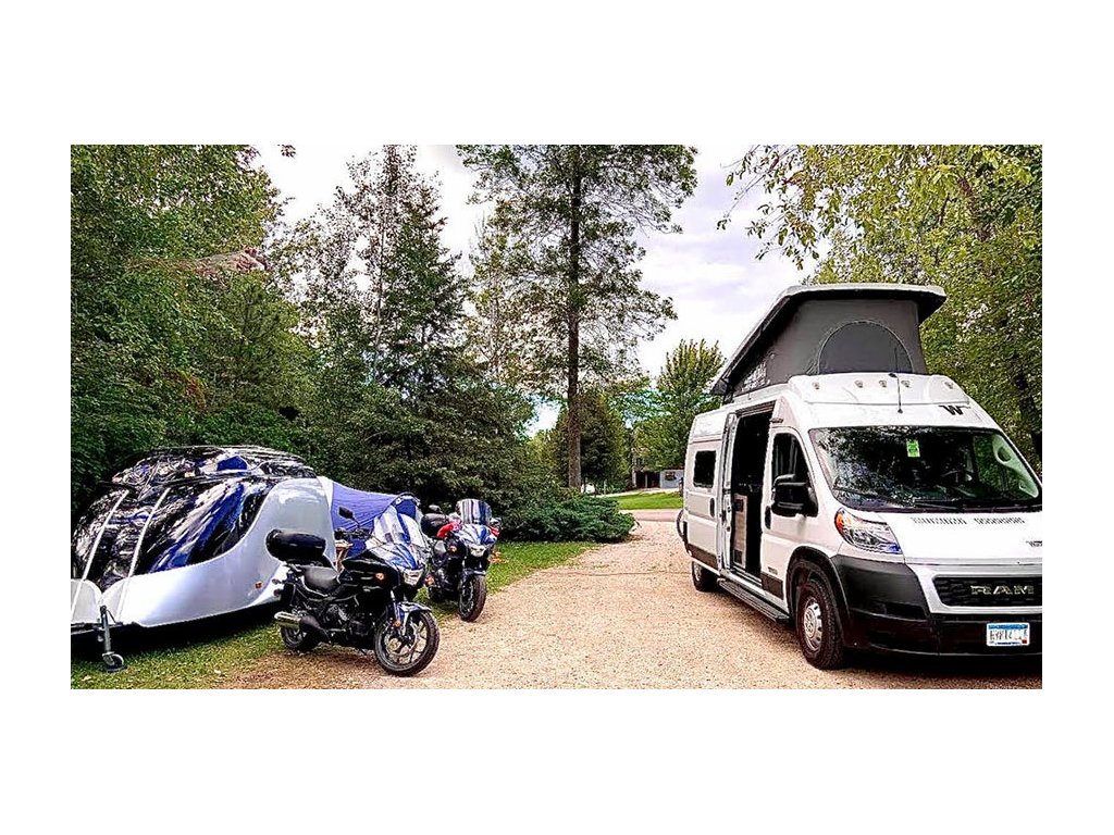 Winnebago Solis parked next to two motorcycles at campsite