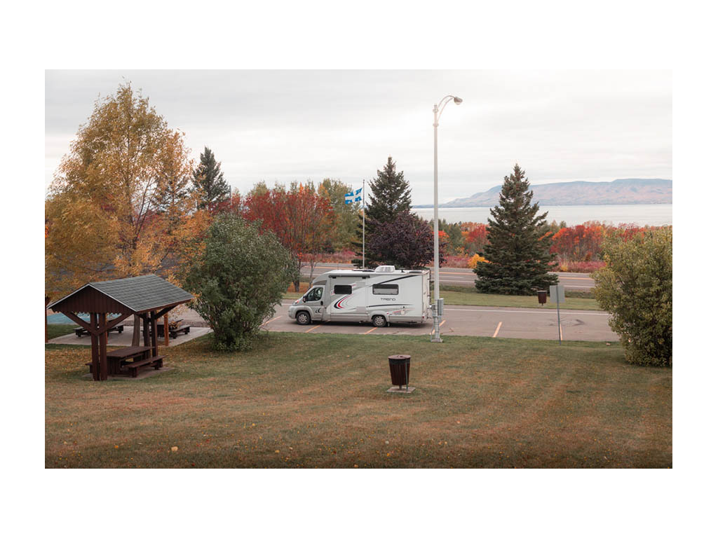 Trend parked in parking lot near pic table. Red fall trees in background.