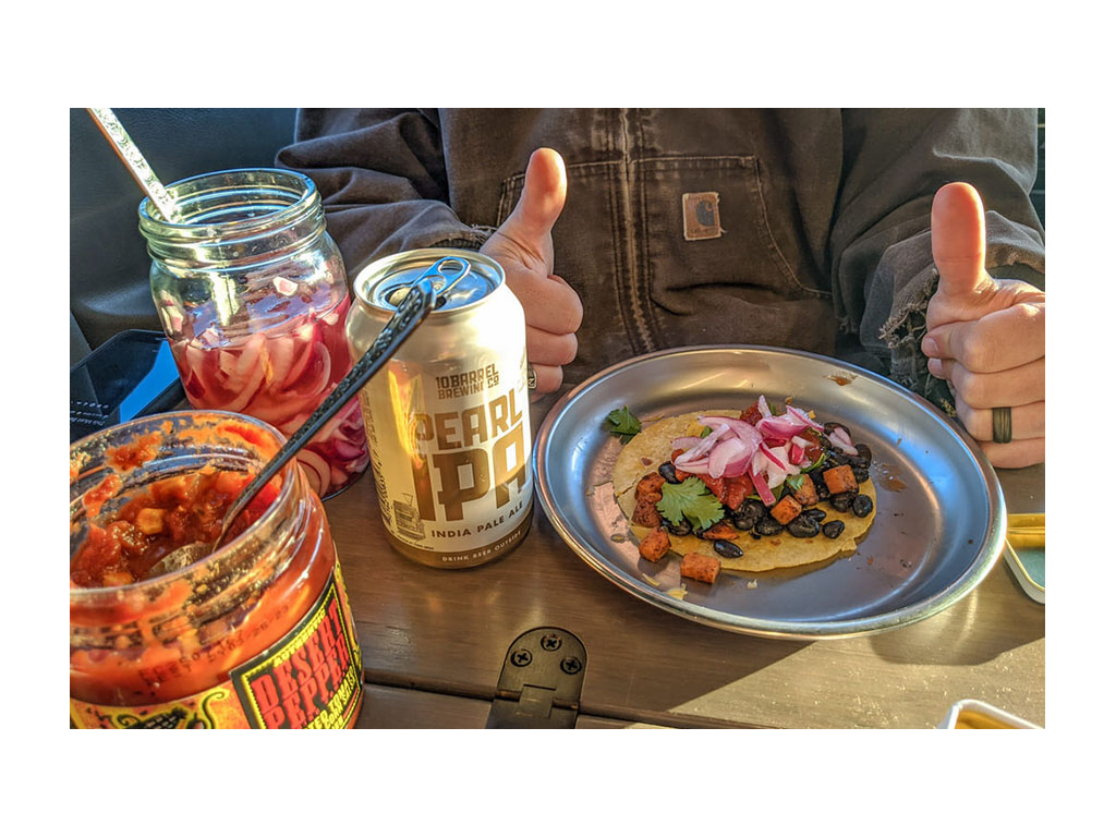 Taco on a plate next to a can of beer and condiments
