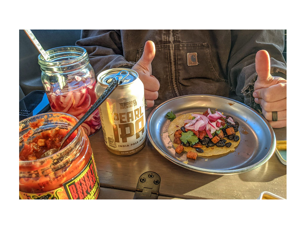 Taco on a plate next to a can of beer and condiments 