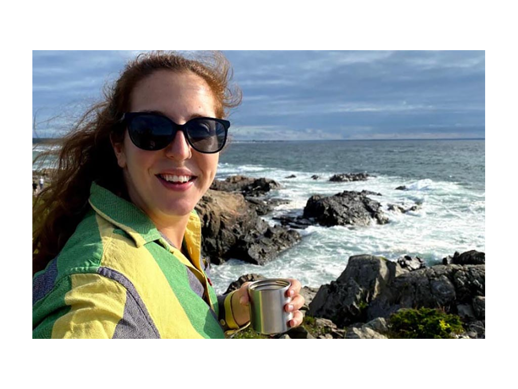 Shanae holding a cup watching the waives in Maine