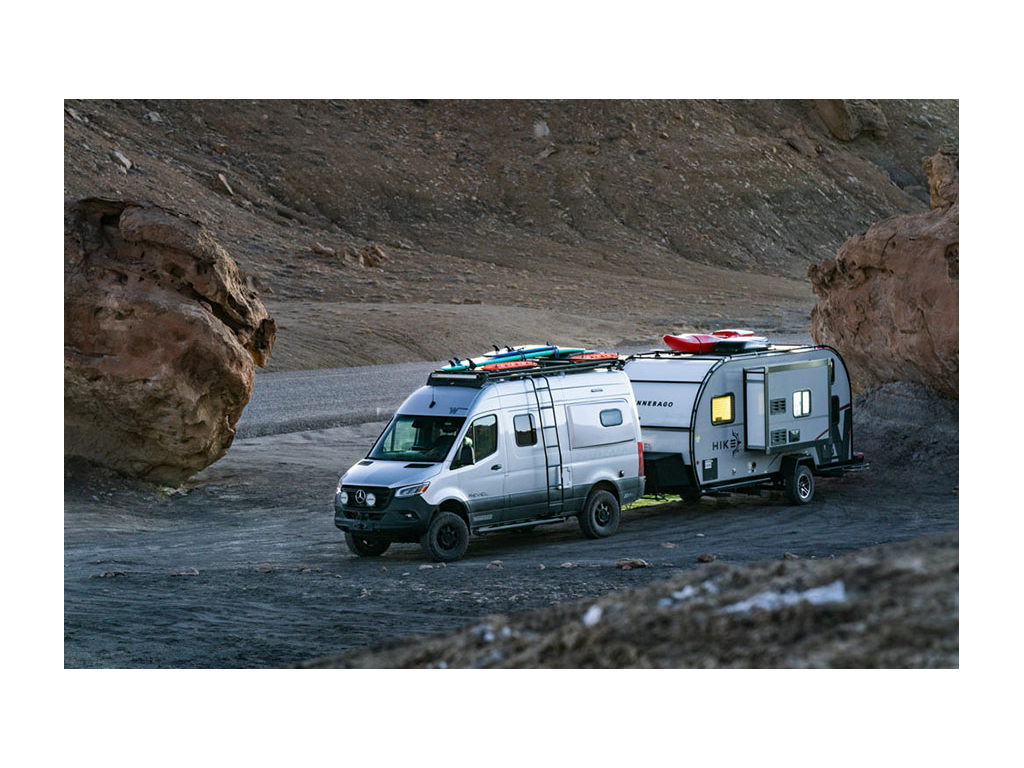 Winnebago Revel pulling Winnebago HIKE with surf boards and kayaks on top