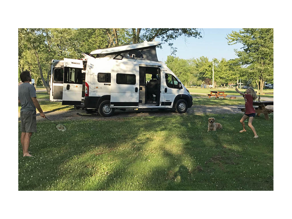 Jason and Mary playing badminton while Bennett lays in the grass