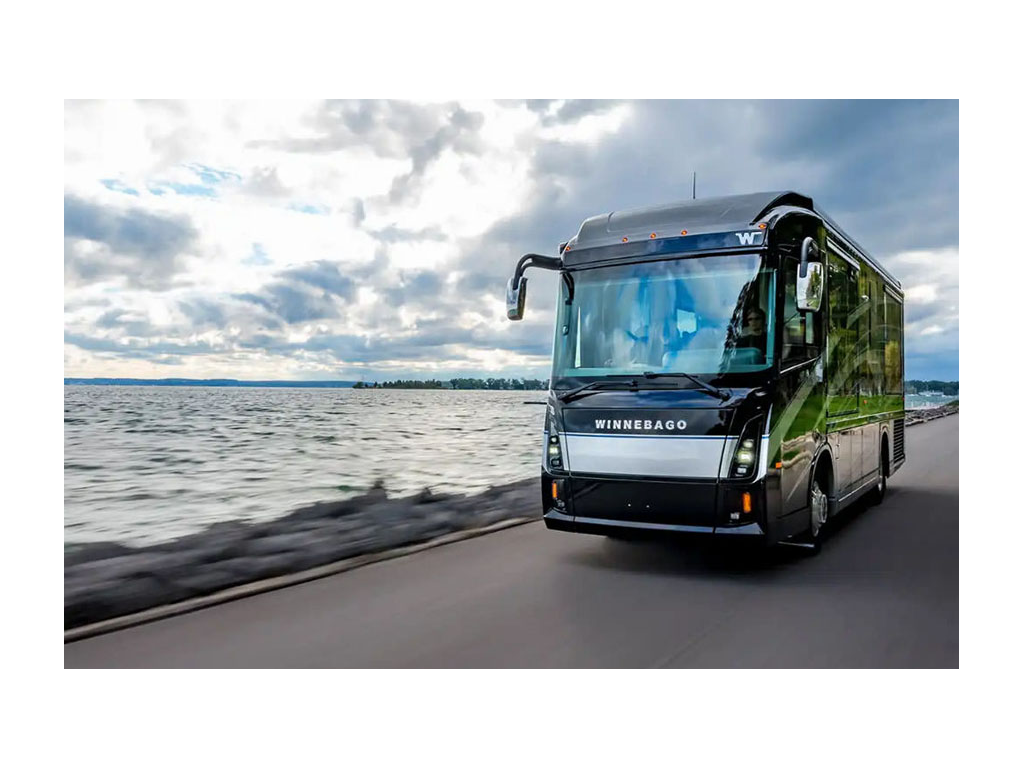 Winnebago Journey driving down road near water.