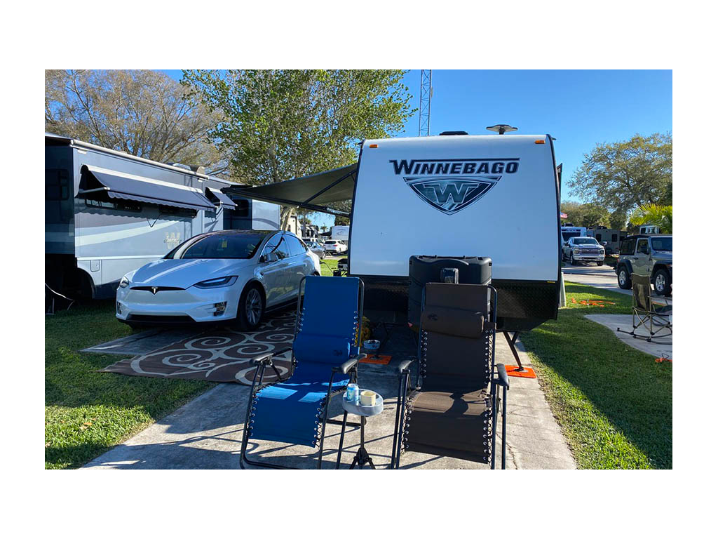 Tesla parked next to Micro Minnie at campsite with two camp chair out in front