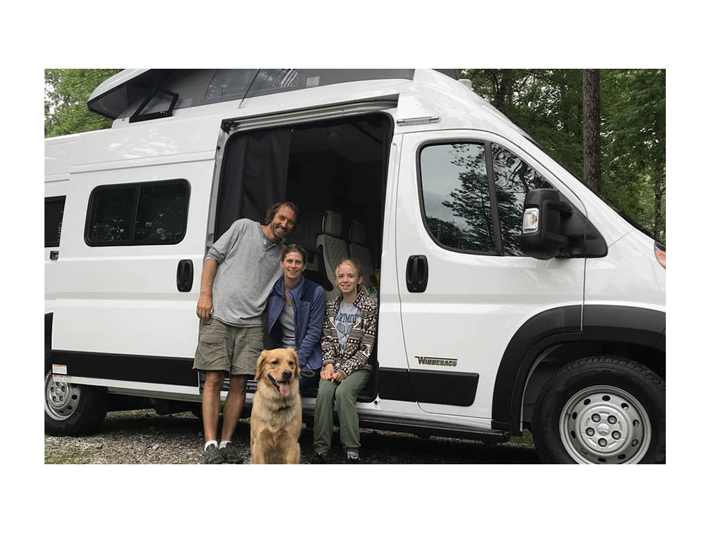 Jason, Kristen, Bennett the dog, and Mary Schmitt sitting in entrance of Solis