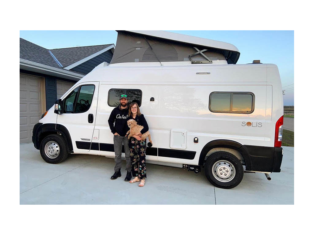 Lindsey and Dan holding their pup in front of Solis