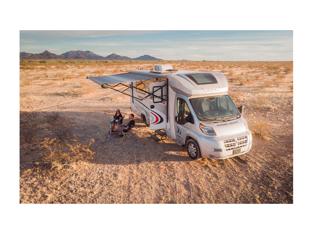 Drone shot of Jon and Nadia sitting in camp chairs outside of Winnebago Trend with awning extended