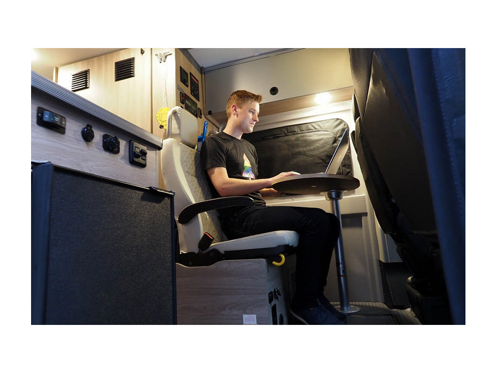 Mikah sitting at dinette seat doing work on laptop