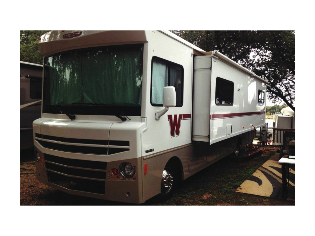 Winnebago Brave with slides out parked in campsite.