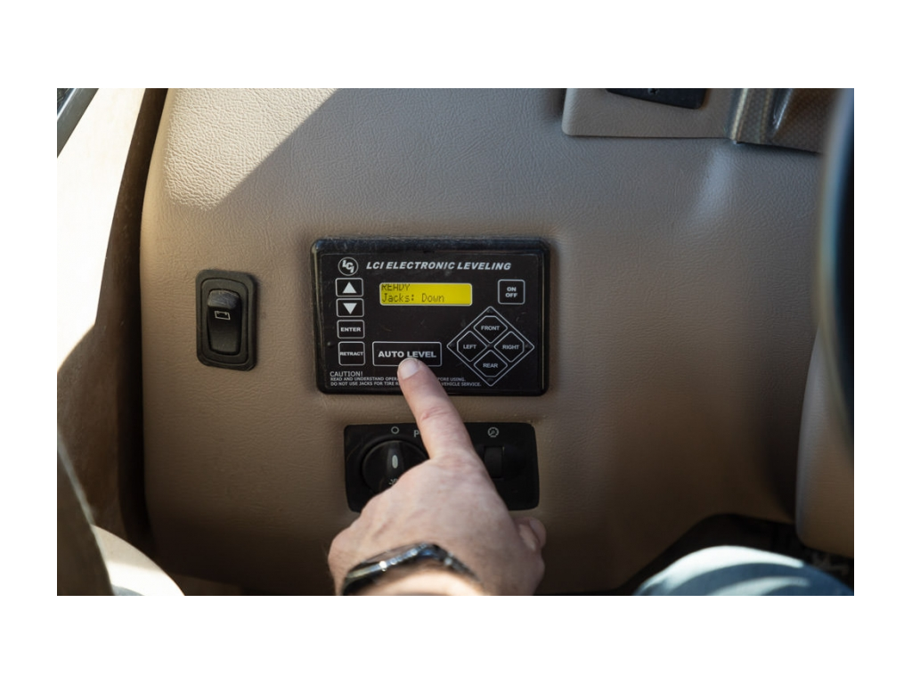 Pressing the auto level button on the auto-leveling system to level RV