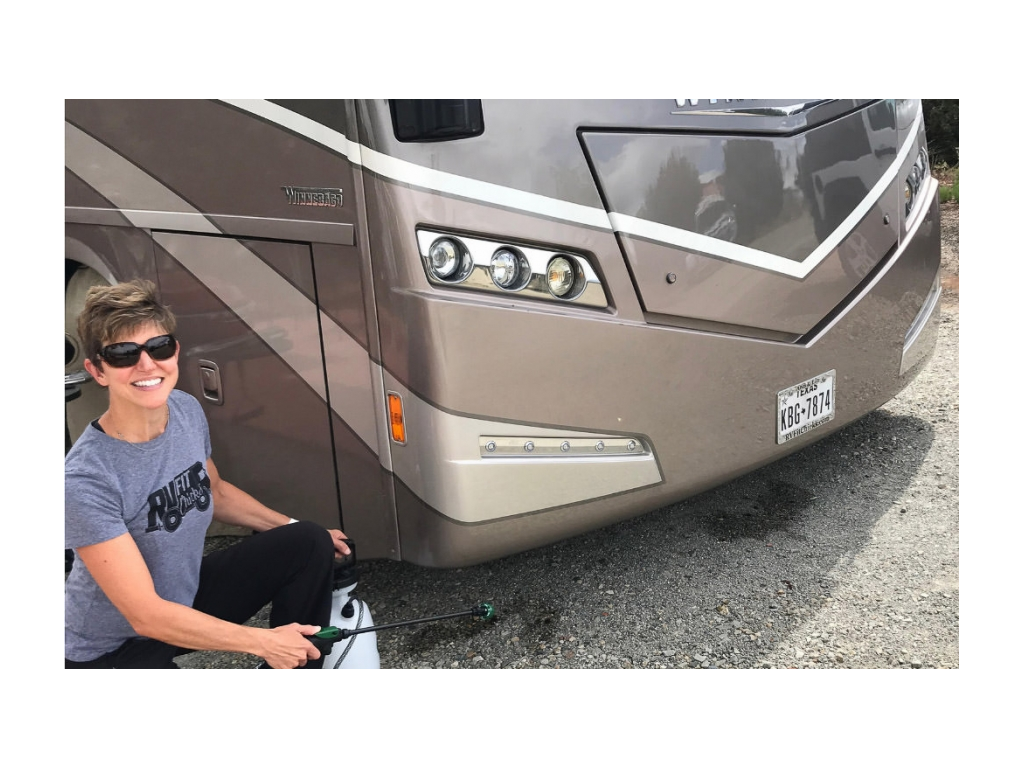 Woman sprays bug spray around campsite and motorhome to repel bugs