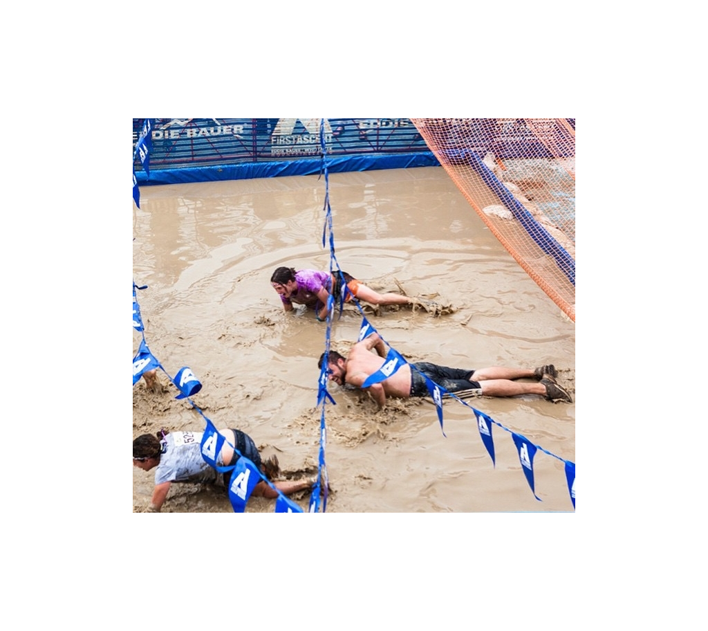 People crawling through the mud of an obstacle course.
