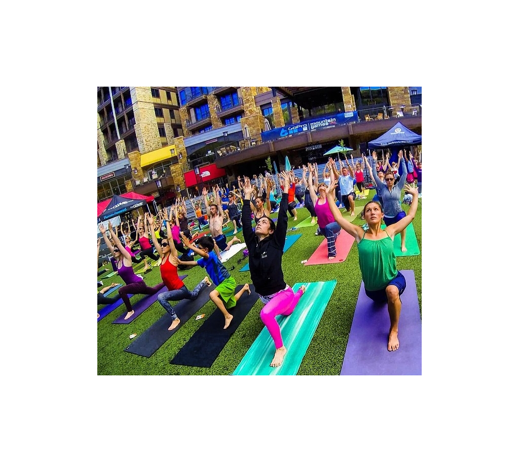 Large group of people doing yoga in the grass.