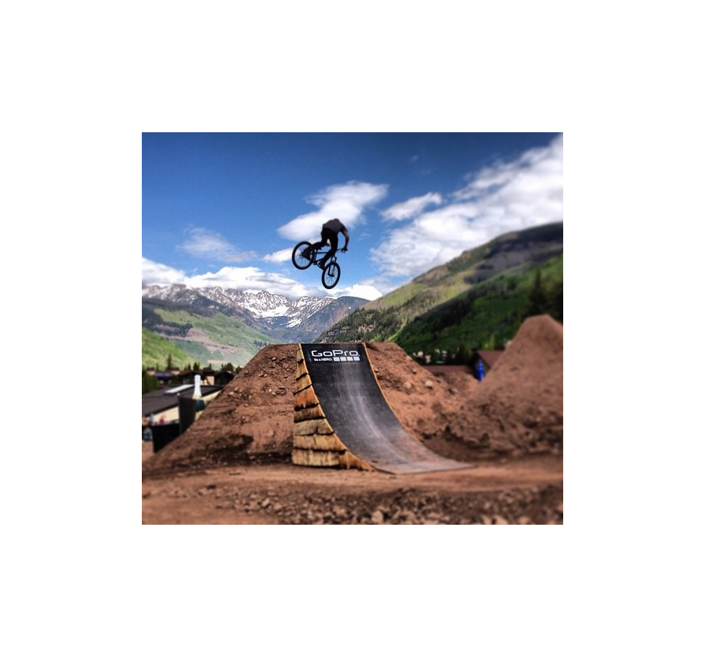 Biker getting air after going off a jump with mountains in the background.