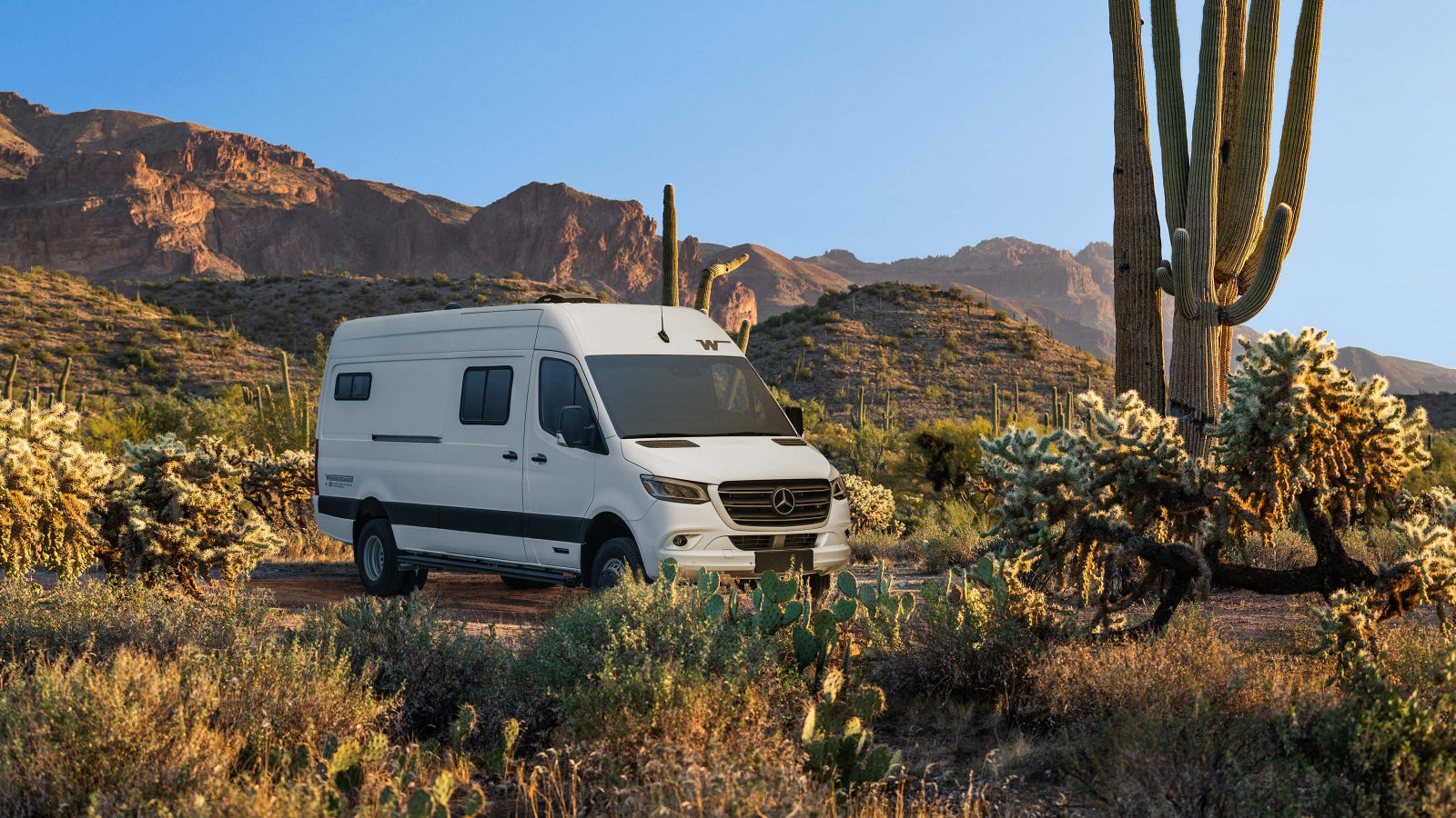 The Winnebago Adventure Wagon in a desert setting, surrounded by cacti and mountains