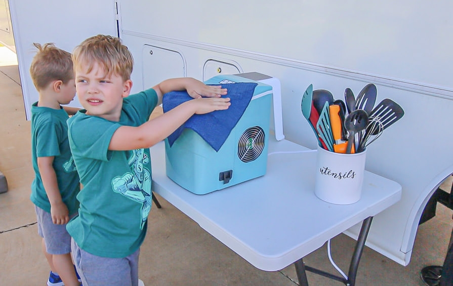 Young boys help with RV spring cleaning and wipe down household accessories