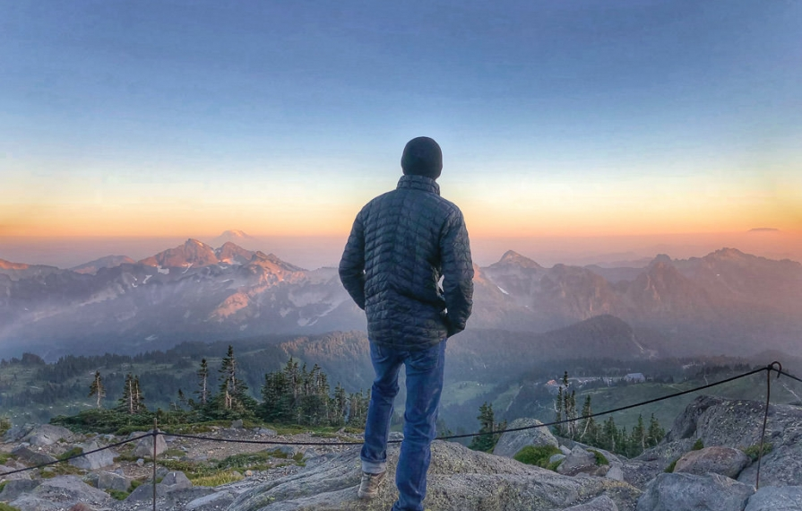 Man looking out over the mountains from a lookout.