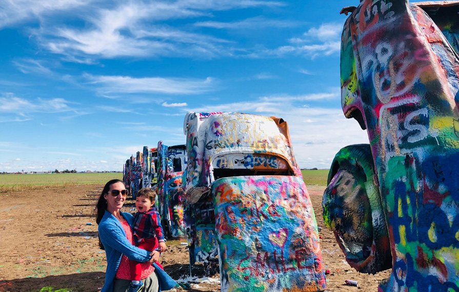 Brittany holding Caspian in front of cars at Cadillac Ranch