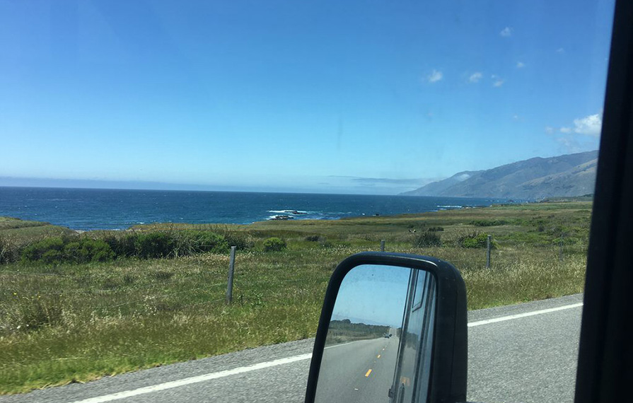 Look out driver's side window of road and ocean
