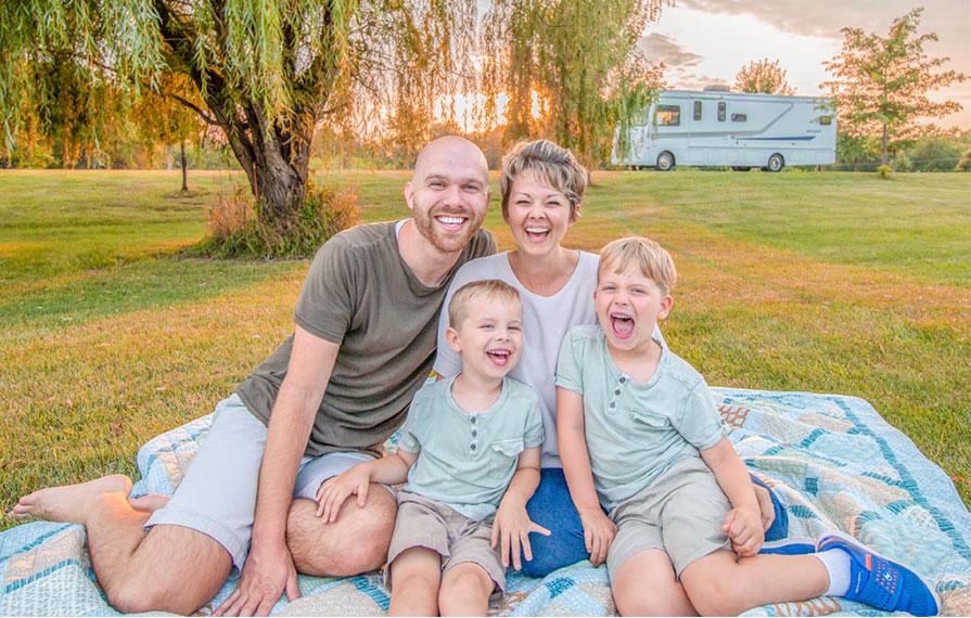 Farish family sitting smiling with beautiful trees and Winnebago Intent in the background
