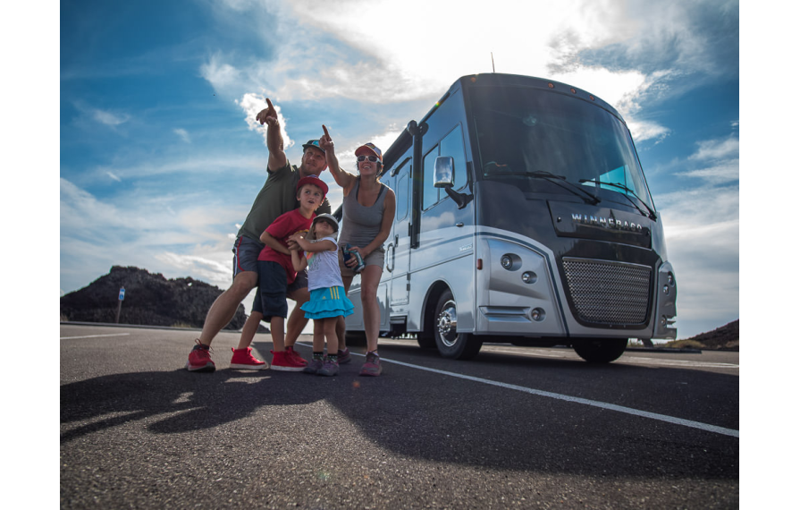 Pyke family outside their Winnebago Adventurer pointing to something in the distance