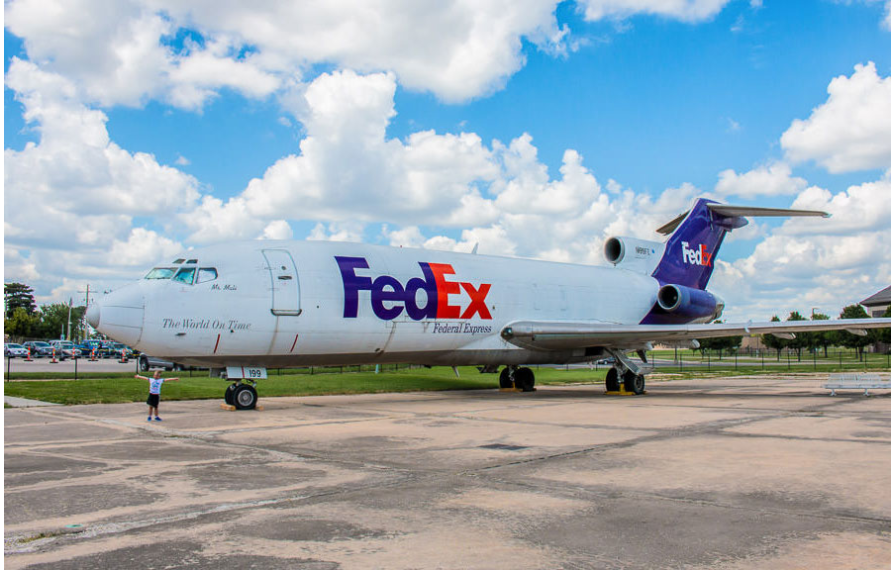 One of the boys next to a FedEx plane at the Kansas Aviation Museum