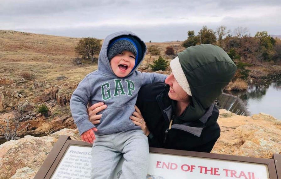 Brittany holding Caspian next to a trail sign