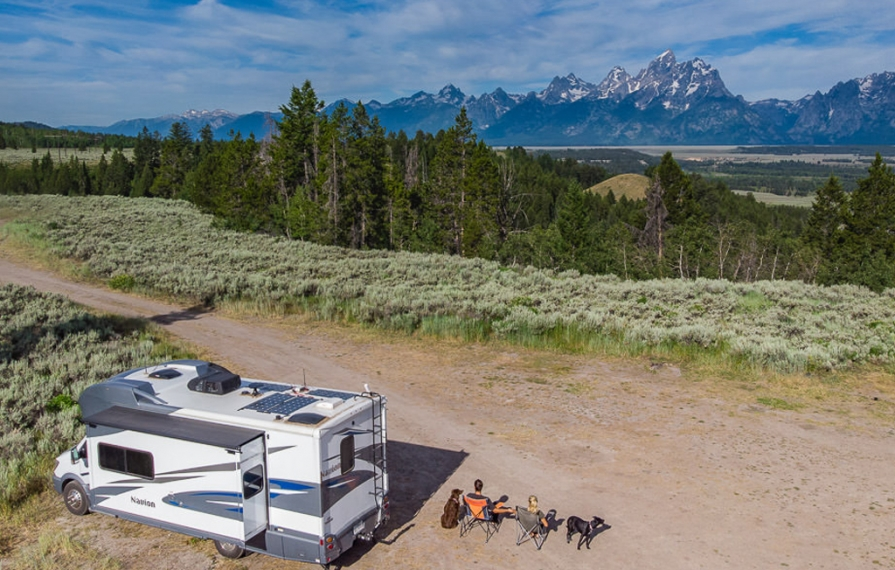 Drone shot of Lindsay, Dan and the dogs sitting in lawn chairs next to the Winnebago Navion