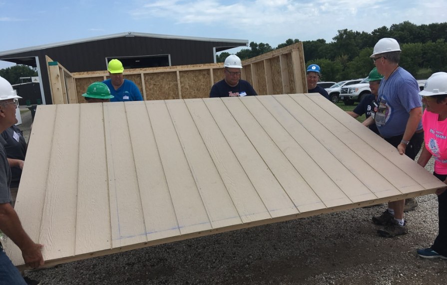 A group of RV Care-A-Vanners lifting up a finished wall