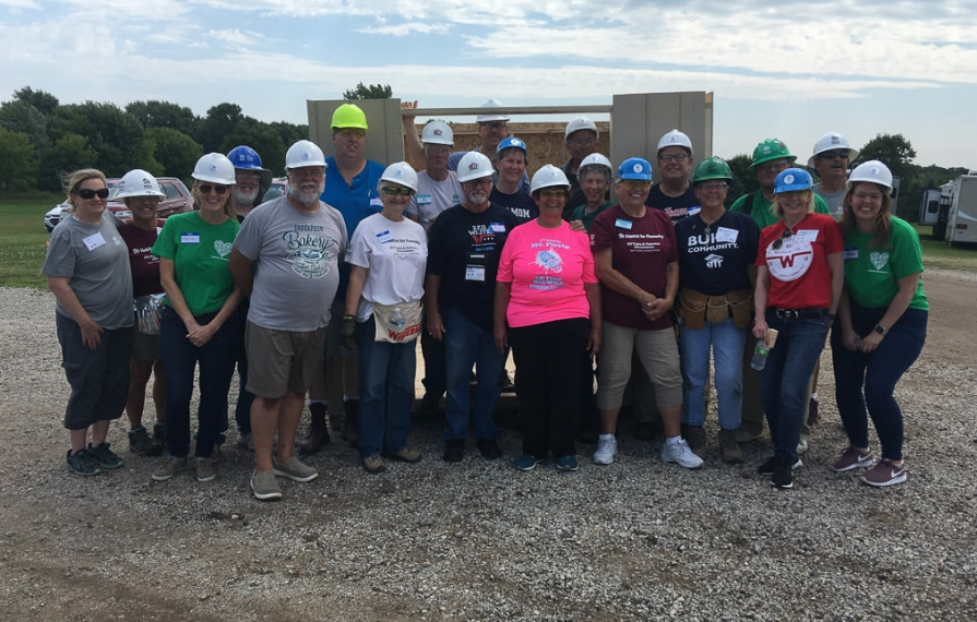 RV Care-A-Vanners huddled in front of shed smiling
