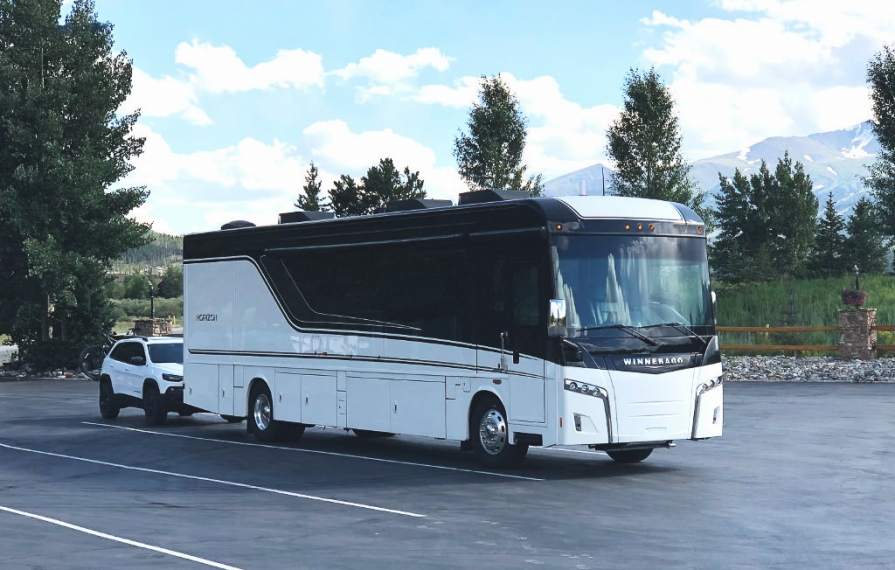 Winnebago Horizon with tow car in parking lot