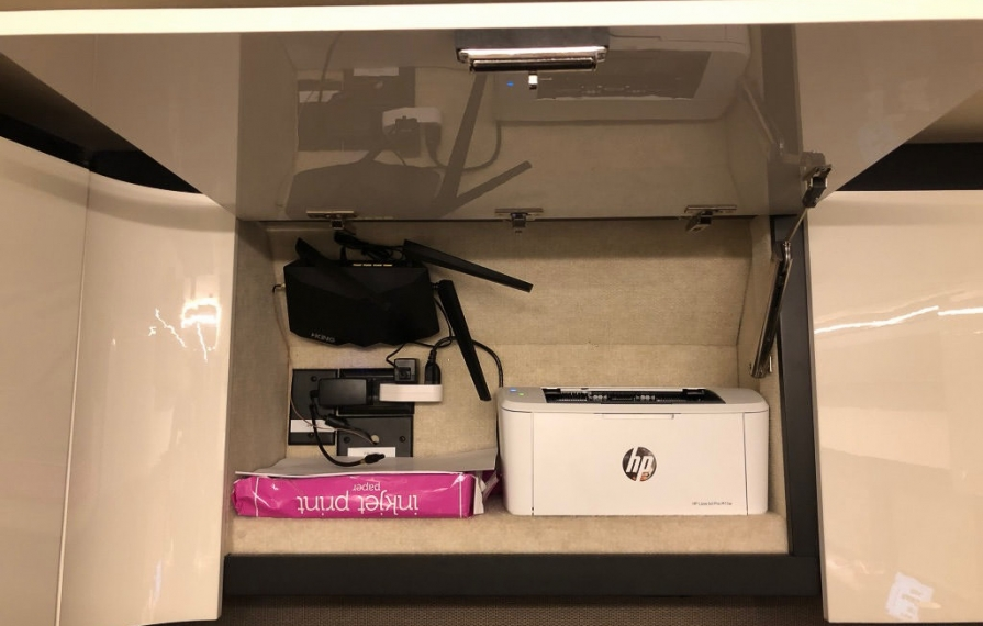 HP printer, printer paper and King Antenna WiFi system in overhead bin
