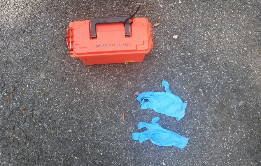 Sewer accessories box and gloves sitting on the ground.