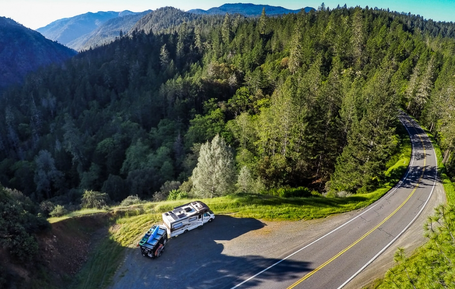 Aerial view of Winnebago View with tow trailer parked on a side road in the mountains