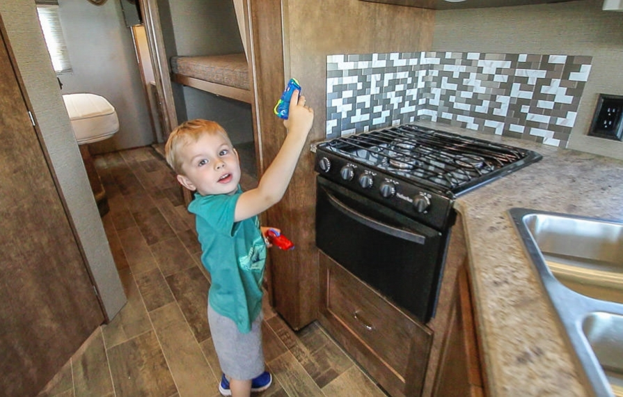 Young man helps with RV spring cleaning using water squirt guns