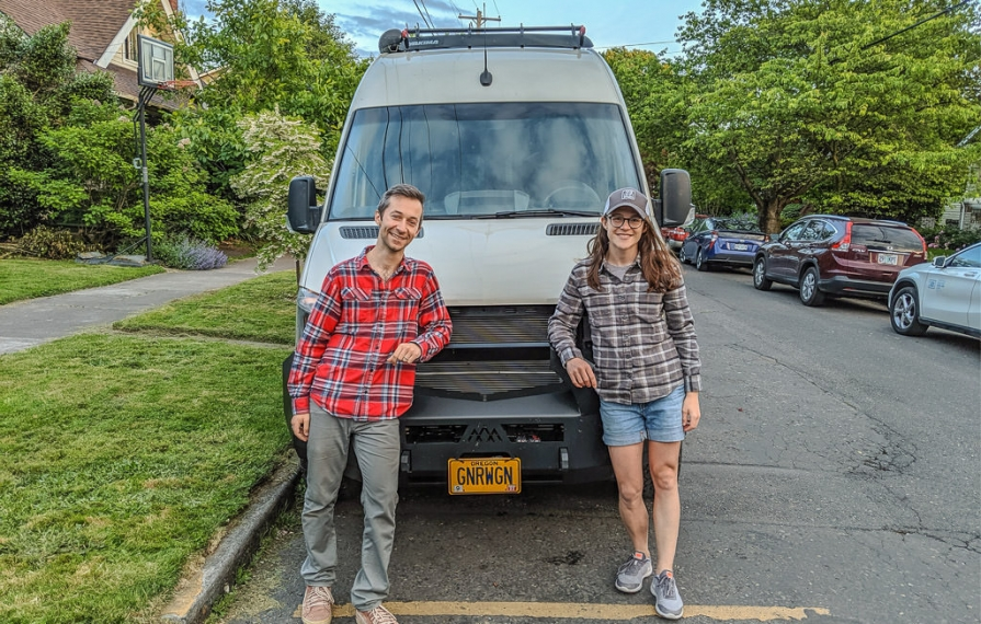 Young couple poses in front of their Winnebago Revel