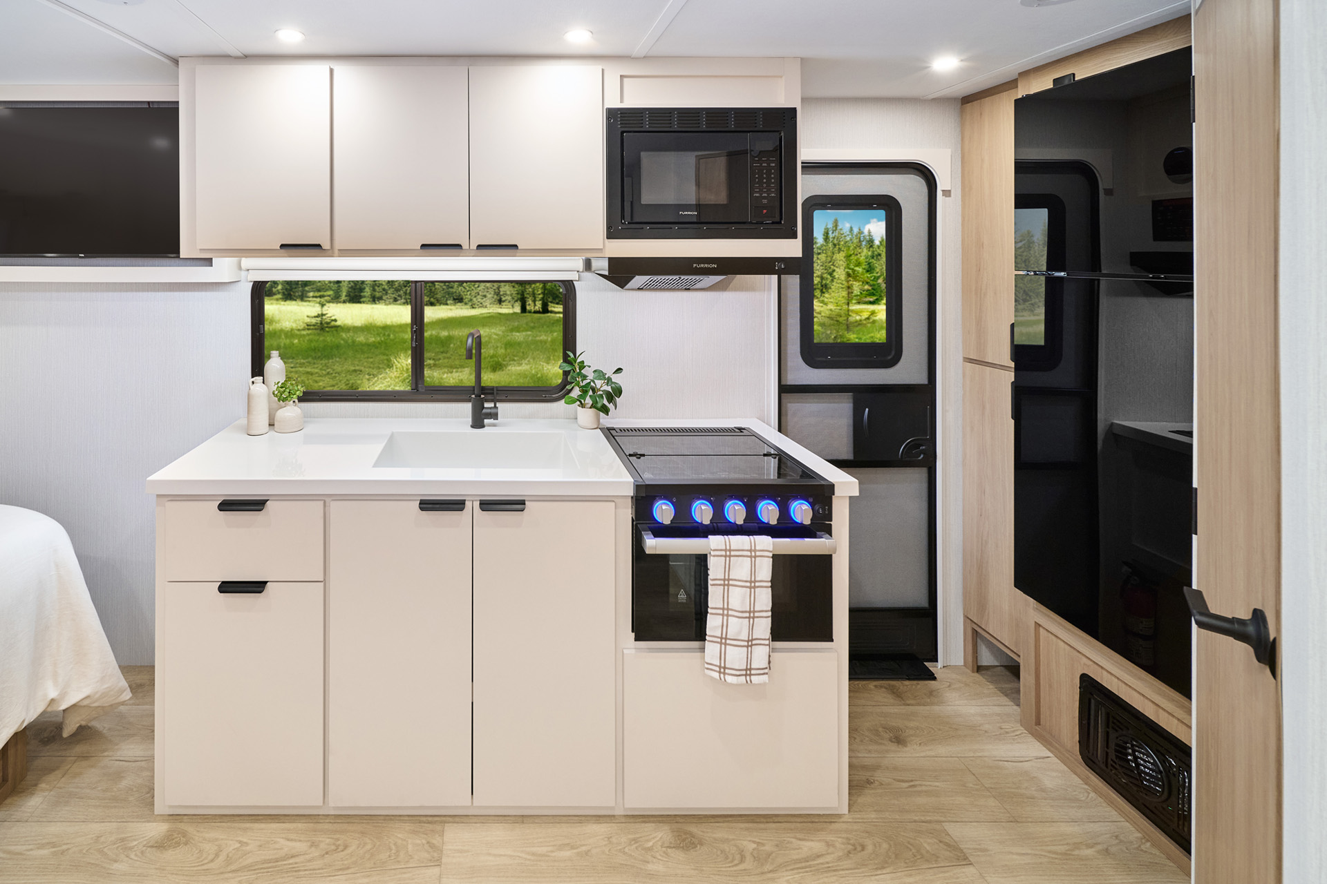 2026 Winnebago Thrive 18FBS — Close up of galley inside the Winnebago Thrive 18FBS, including sink, range, oven, overhead microwave, and full fridge