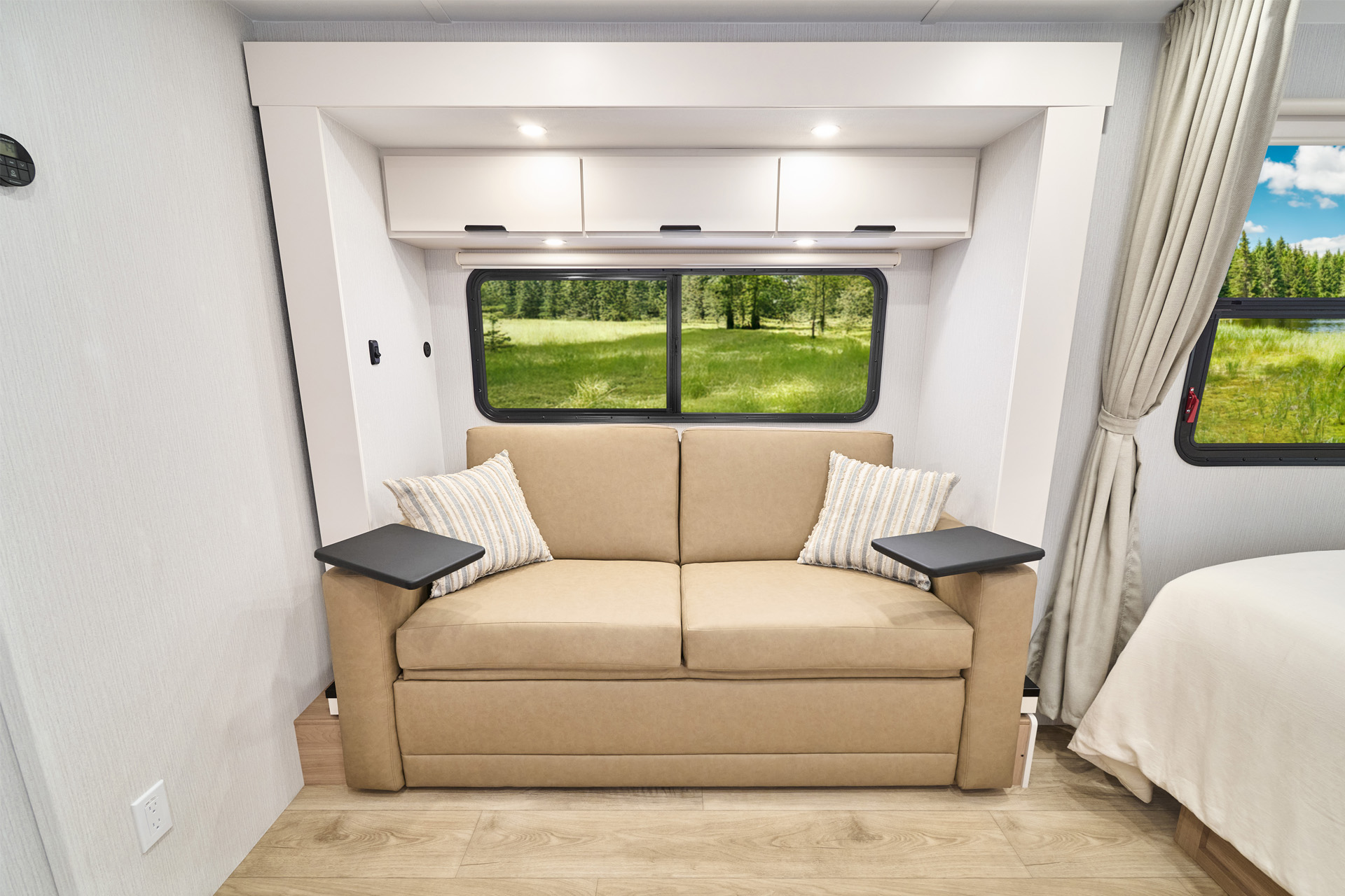 2026 Winnebago Thrive 18FBS — Close up of the sofa inside a Winnebago Thrive 18FBS, including a window and overhead storage