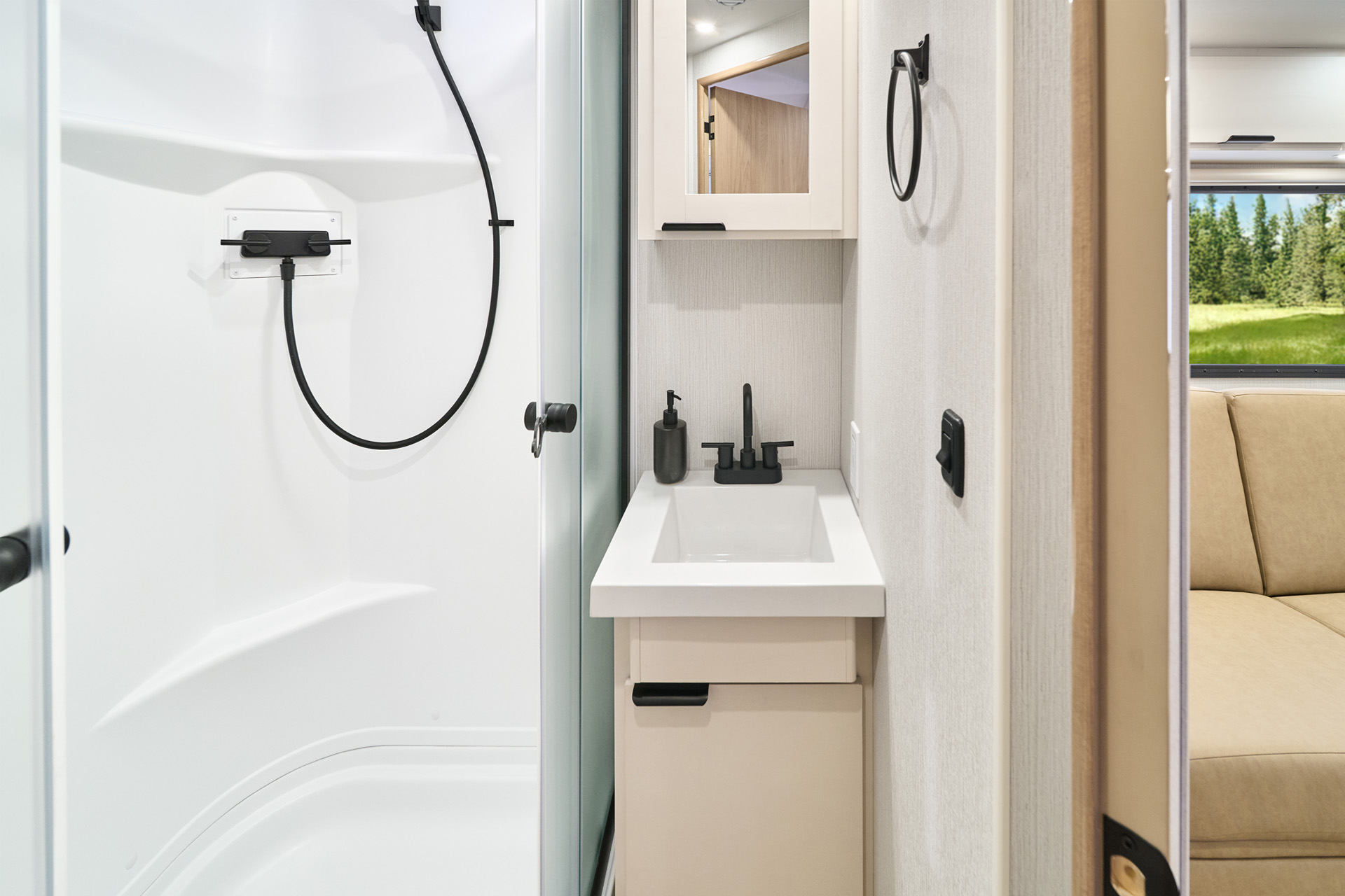 2026 Winnebago Thrive 18FBS — Close up of the bath vanity inside a Winnebago Thrive 18FBS, including a storage cabinet and mirror, sink, and shower