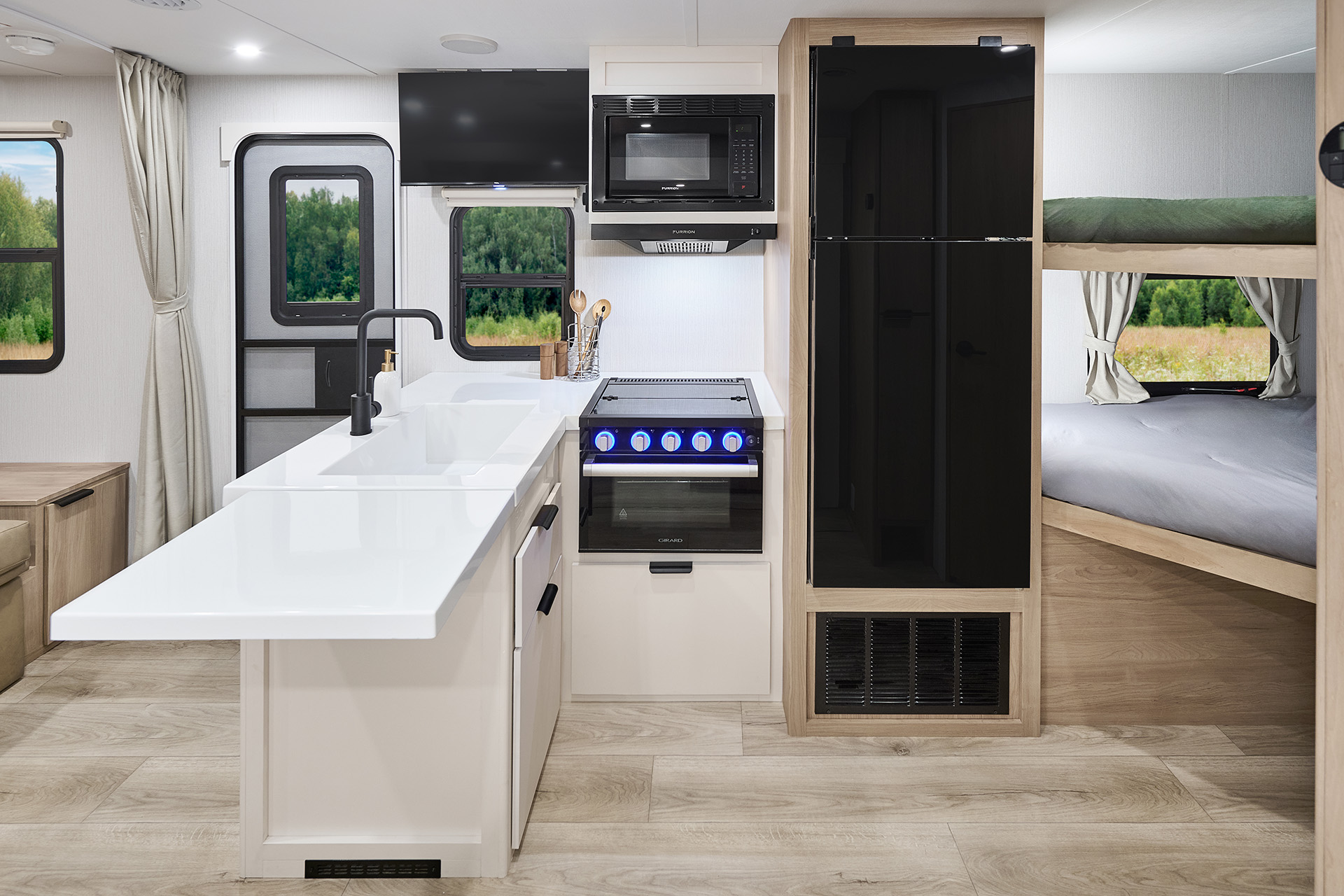 2026 Winnebago Thrive 22MBH — Close up of the galley inside a Winnebago Thrive 22MBH, including extendable counters, full sink, range, oven, overhead microwave, TV, lower cabinets, and full fridge